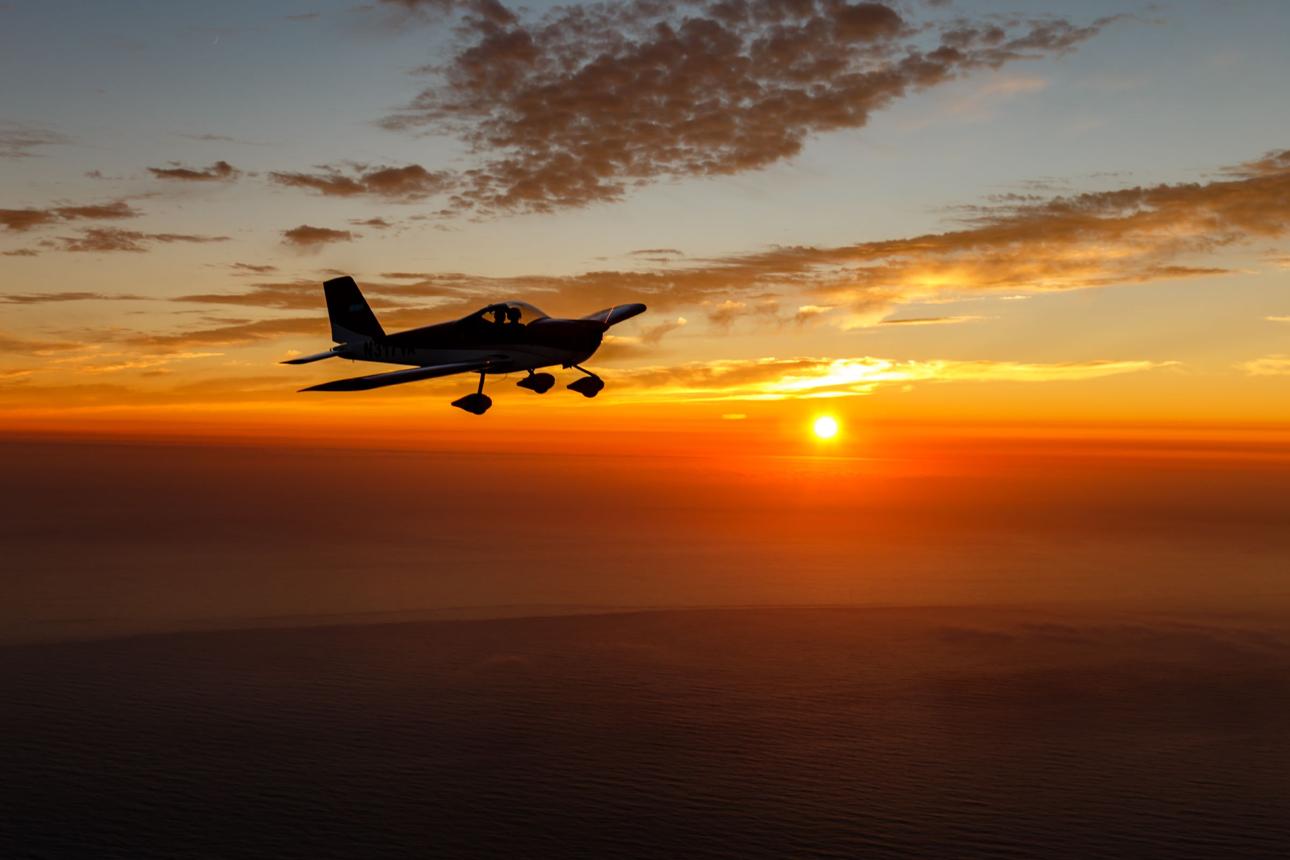 Single-engine trainer aircraft in flight over open countryside